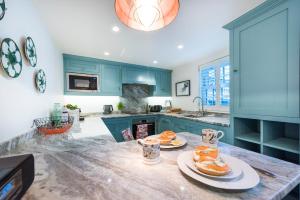 a kitchen with blue cabinets and plates of food on a counter at Juliot 5 Star Gold Award Luxury Cottage in St Ives