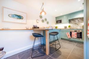 a kitchen with green cabinets and a counter with stools at Juliot 5 Star Gold Award Luxury Cottage in St Ives +4 photos