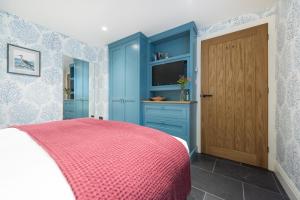a bedroom with a blue cabinet and a television at Juliot 5 Star Gold Award Luxury Cottage in St Ives