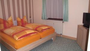 a bedroom with a bed with orange sheets and a television at Ferienwohnung Einenkel in Seiffen