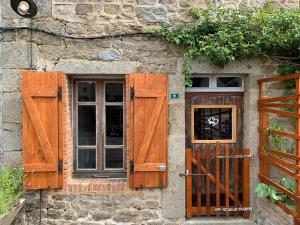 a stone building with wooden doors and a window at Doxie Cottage in Saint-Chabrais