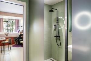 a bathroom with a shower and a woman in a bedroom at Hotel Unplugged in Rotterdam