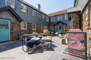 a patio with a table and chairs in front of a building at The Garth 5 Star Gold Luxury Cottages in St Ives