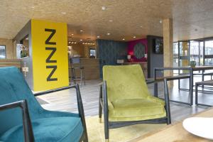 a lobby with a yellow chair and a table at Snoozebox Olympic Park in London
