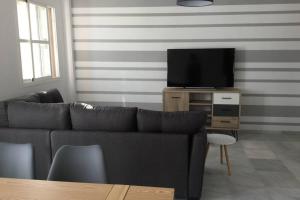 a living room with a couch and a flat screen tv at Dúplex muy cerca de la playa y del centro in Tarifa