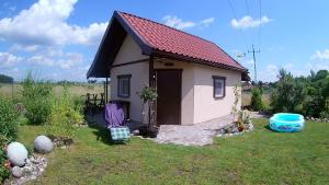 een klein huis met een rood dak in een tuin bij Noclegi Pod Dachem pokoje gościnne domek letniskowy na wynajem agroturystyka wakacje in Sajzy