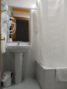 a white bathroom with a sink and a mirror at Hotel Los Robles in Cangas de Onís