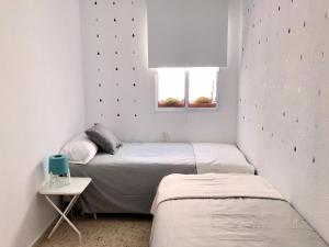 2 camas en una habitación pequeña con ventana en Apartamento La Barrosa, en Chiclana de la Frontera