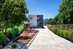 Un jardín con un camino de ladrillos que conduce a una casa. en Mandalina HR Luxury Villa with Private Pool, Tennis Court and Boccie Alley, en Donji Proložac