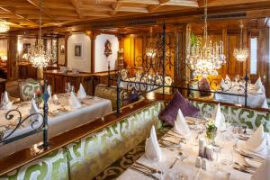 une salle à manger avec des tables blanches et des lustres dans l'établissement Hotel Sonne, à Zermatt