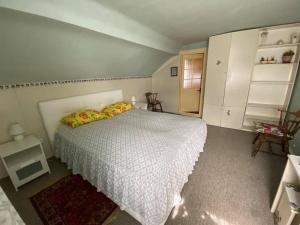 ein Schlafzimmer mit einem Bett mit einer weißen Tagesdecke in der Unterkunft Butas Prie Marių in Juodkrantė