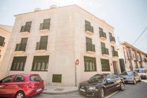 dos coches estacionados frente a un edificio en Apartamentos Plaza de Santiago - Estudios Turisticos - 1 LLAVE, en Pinto