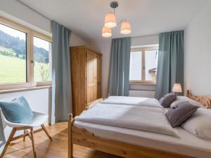 sypialnia z łóżkiem, krzesłem i oknami w obiekcie Chalet Achenberg w mieście Brixen im Thale
