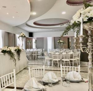 特雷比涅的住宿－貝爾維尤酒店，宴会厅配有白色的桌子和白色的椅子