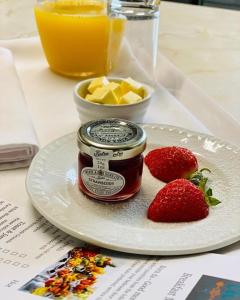 a plate with a jar of jam and strawberries on a table at Cwtch Guesthouse in Llandudno