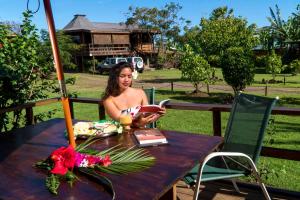 una mujer sentada en una mesa leyendo un libro en Cabañas Tokerau, en Hanga Roa