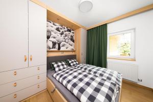 ein Schlafzimmer mit einem schwarz-weiß karierten Bett in der Unterkunft VRÁTNA Apartmány Stoh A1 a C1 in Terchová