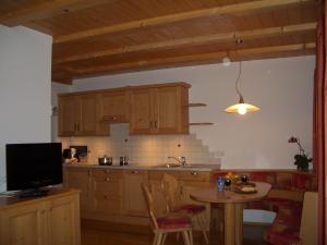 a kitchen with wooden cabinets and a table and a tv at Lafreiderhof in Castelrotto