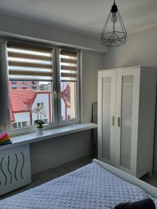 a bedroom with two windows and a bed with a table at Apartament przy promenadzie in Ełk
