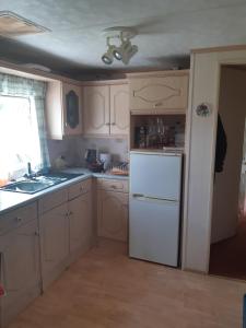 a kitchen with white cabinets and a white refrigerator at Domek holenderski in Łuka