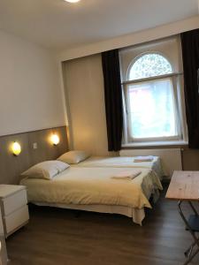 2 camas en una habitación con ventana en hotel Oosterpark, en Ámsterdam