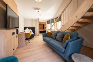 a living room with a blue couch and a staircase at Hotel Bradabella - Montafon in Gargellen