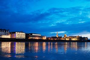 a view of a city at night with the water at Oceania Saint Malo in Saint Malo