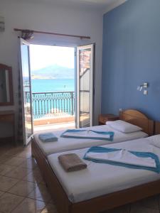 two beds in a room with a view of the ocean at Hotel Damo in Pythagoreio +17 photos