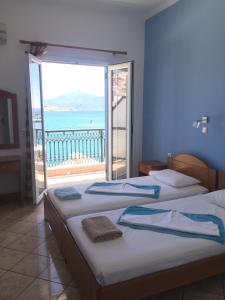 two beds in a room with a view of the ocean at Hotel Damo in Pythagoreio