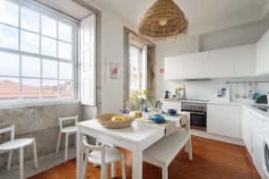 ポルトにあるOwn Places Clérigos Apartmentsの白いキャビネット、テーブルと椅子付きのキッチンが備わります。