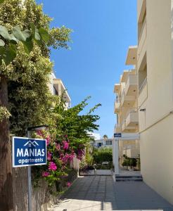 een bord op een stoep naast een gebouw met bloemen bij Manias Apartments in Kos-stad