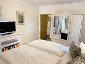 a bedroom with a white bed and a television at Ostseehaus Dreesen in Timmendorfer Strand