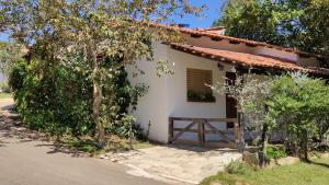 una pequeña casa blanca con una puerta y árboles en Chalés Beira Rio en Pirenópolis