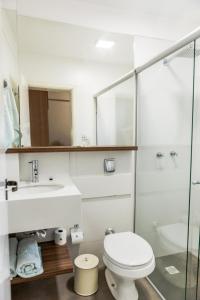 a white bathroom with a toilet and a sink at Hotel União in Teutônia
