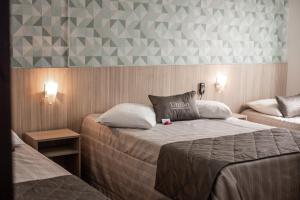 TeutôniaにあるHotel Uniãoのベッドルーム1室(ベッド2台付)と壁が三角形になっています。
