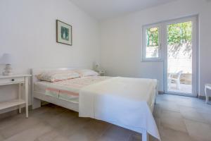 a white bedroom with a bed and a window at NeMo in Povile