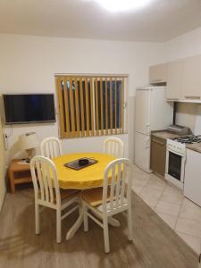 uma pequena cozinha com uma mesa amarela e cadeiras em Apartments Jerković Drašnice-3bd em Drašnice