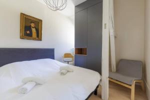 ein Schlafzimmer mit einem weißen Bett und einem Stuhl in der Unterkunft Magnifique appartement au cœur de la Petite France in Straßburg