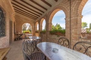 een patio met tafels, stoelen en bogen bij Il Canto del Sole in Monteroni dʼArbia
