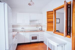 cocina con armarios blancos, fregadero y ventana en Casa Calle Cordoba, en Chipiona