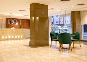 a lobby with green chairs and a table in a building at Sela Hotel in Al Madinah