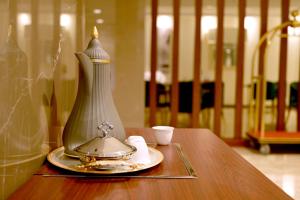 een vaas op een tafel met een bord en een beker bij Sela Hotel in Al Madinah