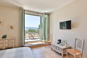 a bedroom with a bed and a tv and a balcony at Quintessence Provence in Goult