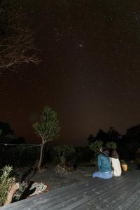 Kumage-gun - House - Vacation STAY 89468 في Yudomari: شخصان يجلسون على الشاطئ ينظرون إلى النجوم
