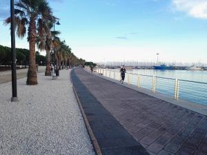 a person walking down a sidewalk next to the water at Your home in Bonaria in Cagliari