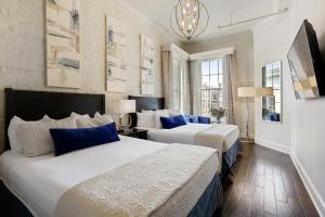 two beds in a hotel room with blue pillows at La Galerie French Quarter Hotel in New Orleans +40 photos