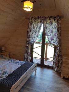 a bedroom with a bed and a large window at Domek na wzgórzu "RYŚ" in Krempna