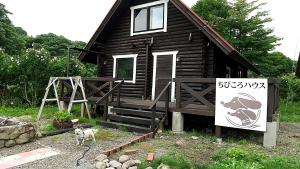una cabaña de madera con un perro parado fuera de ella en Maniwa - Cottage - Vacation STAY 90022, en Maniwa