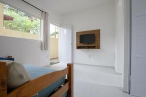 1 dormitorio con 1 cama y TV en la pared en Recanto do Camargo, en Ubatuba