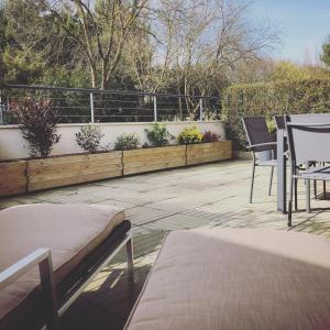 eine Terrasse mit Stühlen, Tischen und einem Zaun mit Pflanzen in der Unterkunft Le Petit Caillebotis in La Rochelle